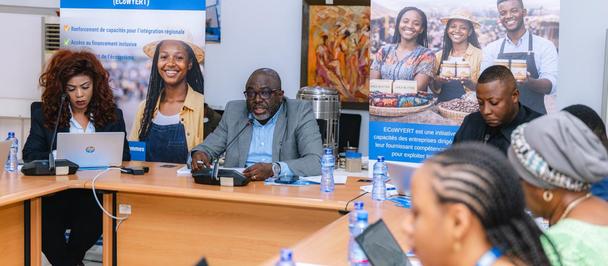 Diverse group at a conference table with laptops; banners in the background.