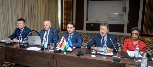 Photograph of five panelists in suits seated at a conference table with microphones.