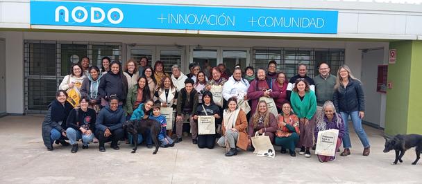 Group photo of diverse people posing outside a building with NODO signage.