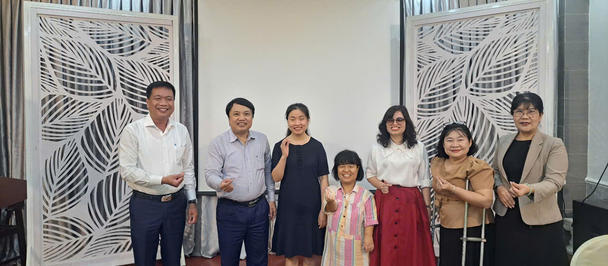 Group of eight people posing in a decorated hall with white lattice screens.