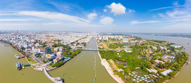 Panoramic aerial view of a coastal town with a river, canal, bridges, and green neighborhoods.