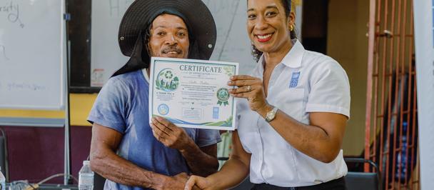 UNDP Asisstant Resident Representative hands over certificate to welder Garth Martin of Petersfield in Westmoreland