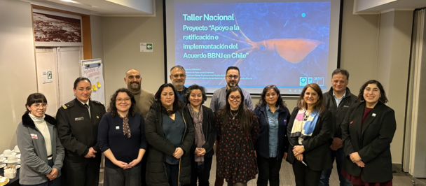 Diverse group of professionals posing in a conference room in front of a projector screen.