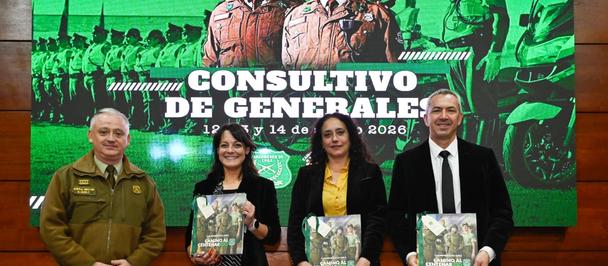Group of five people posing with books on a stage in front of a green banner featuring soldiers.