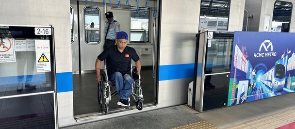Photograph of a man in a wheelchair exiting a blue-and-white train at a platform.