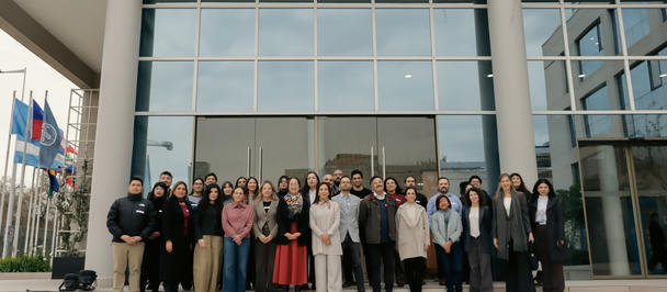 Group of people posing on steps outside a modern glass-front building.