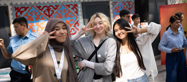 Group of friends posing for a photograph outdoors in front of a blue patterned wall.