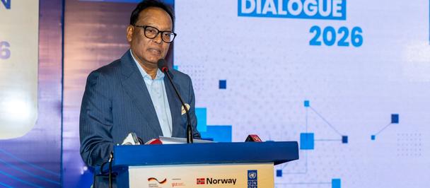 Man at conference podium on blue stage; backdrop reads Social Cohesion Dialogue 2026.