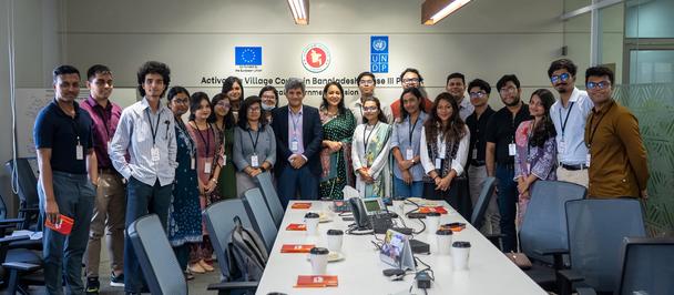Diverse group of colleagues posing for a photo around a long conference table.