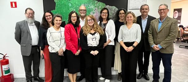 Group of professionals posing for a photo in an office lobby in front of a green mural.