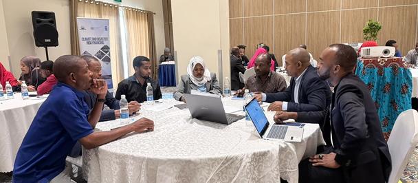Group of people around a round table with laptops in a conference room.