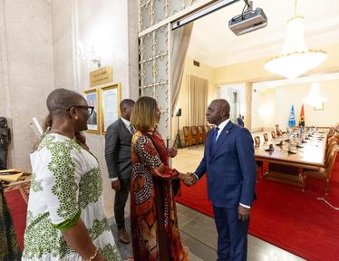 A formal handshake between two dressed individuals in a government setting.