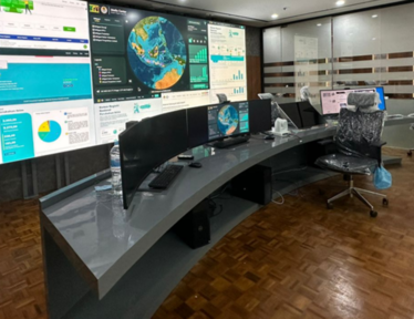 Modern workspace with multiple monitors displaying data and graphs, sleek curved desk.