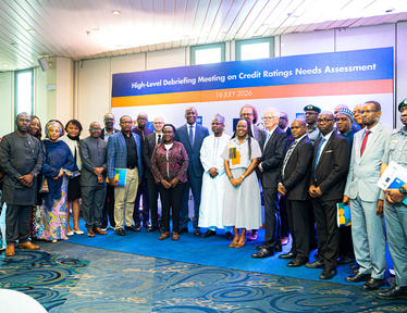 Diverse group of professionals posing for a conference photo in a hall with a blue banner.