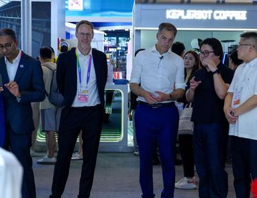 Group of professionals at a blue trade show booth, wearing badges.