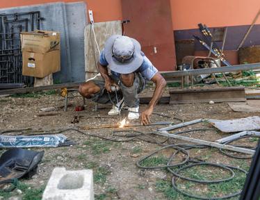 Welder at work recycling hurricane melissa trash