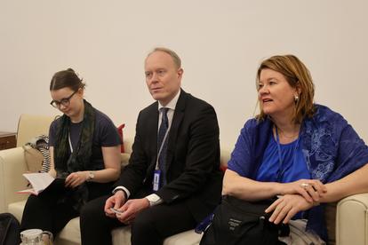 Three professionals seated on a couch, engaging in discussion indoors.
