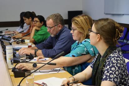 A diverse group of people seated around a conference table engaged in discussion.