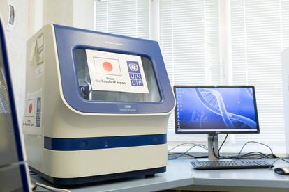 Laboratory setting featuring a DNA sequencer next to a computer monitor.