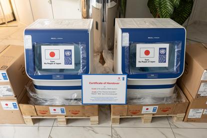 Two blue and white machines with certificates on pallets in a bright room.