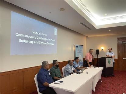 A panel of speakers at a conference discussing public budgeting and service delivery.