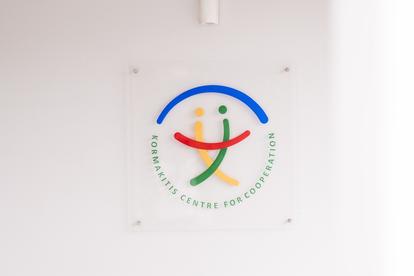 Logo of Komunitas Centre for Cooperation featuring colorful human figures and curved lines.