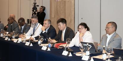 A diverse group of professionals seated at a conference table, engaged in discussion.