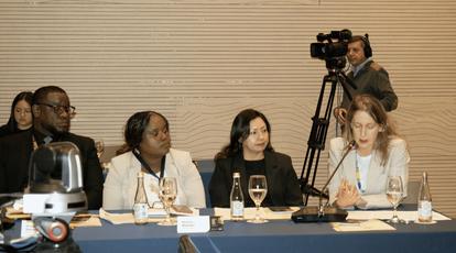 Five individuals seated at a conference table, with a camera recording them.