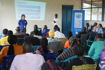 Group meeting with diverse participants, one presenting, and a UNDP logo in the background.
