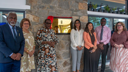 A diverse group of six people stands in front of a stone wall, smiling together.