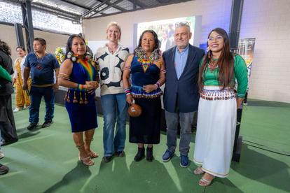 Five individuals pose together in a colorful indoor setting, showcasing traditional attire.