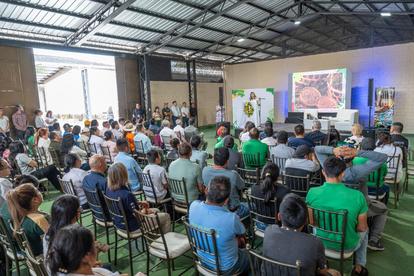 Audience seated in a large venue facing a presentation screen with colorful graphics.