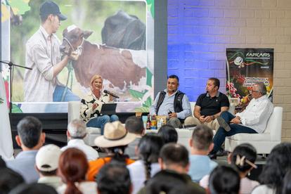 Panel discussion with four speakers, audience in foreground, nature-themed backdrop.