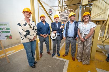 A group of five individuals in hard hats smiles together at a construction site.