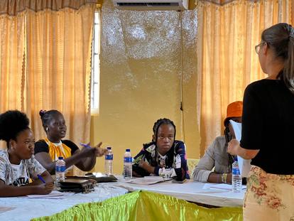 A group discussion with five women sitting around a table, listening to a speaker.