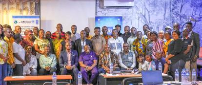 A large group of individuals smiling and posing together in a conference room setting.