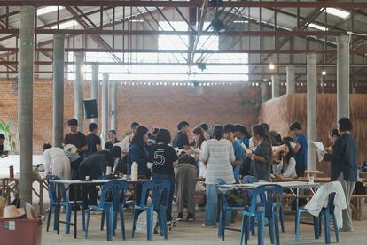 A group of people gathered around tables in a spacious indoor setting.