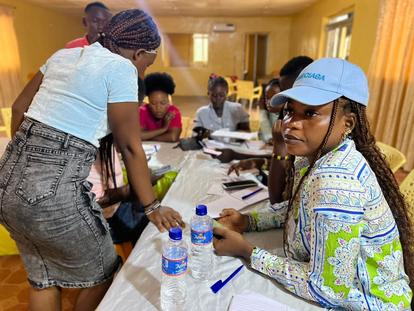 A group of individuals gathered around a table, engaged in discussion with notebooks and water bottles.