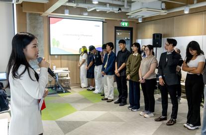 A speaker presents to a group lined up in a modern indoor setting.
