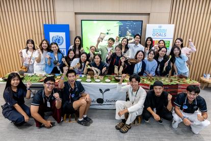 A diverse group of people smiling and posing together in a conference setting with food displayed.