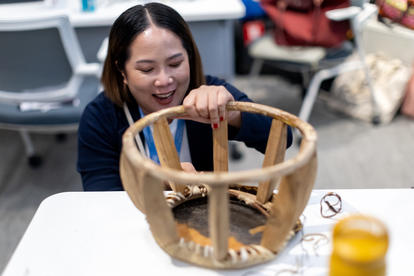 A woman examines a handcrafted bamboo basket, smiling as she inspects the details.