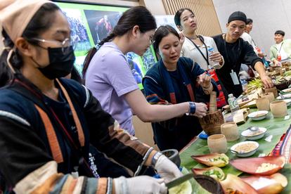 A group of people preparing food together, focused on various ingredients and utensils.
