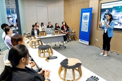 A speaker delivers a presentation to a seated audience in a modern conference room.