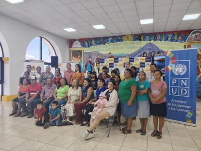 Group portrait of diverse people indoors beside a UNDP banner.