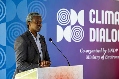 Photograph of a man in a suit at a podium speaking at a climate dialogue event.