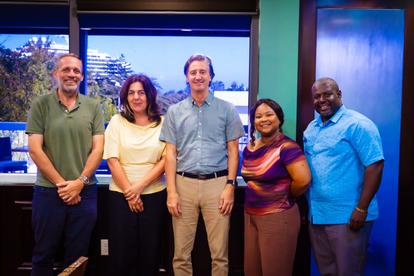 Photograph of five people posing in a TV studio with blue screens behind.