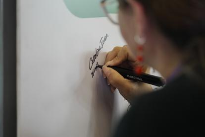 Close-up of a person writing on a whiteboard with a marker.
