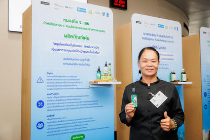 Blurred person in a black shirt at a trade show booth with tall blue posters and product samples.