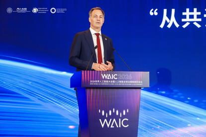 Male presenter in a suit at a WAIC podium on a blue stage with flowing light design.