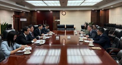 Photograph of executives seated around a long wooden conference table in a boardroom.